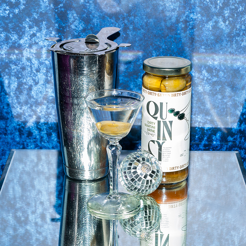 Quincy Dirty Martini Brine & Olives jar next to shaker and cocktail glass